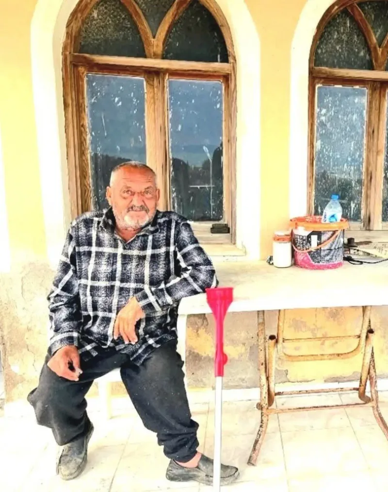 Kareli gömlek giyen yetmiş bir yaşındaki Osman Güntaş bir masanın önündeki sandalyede oturuyor